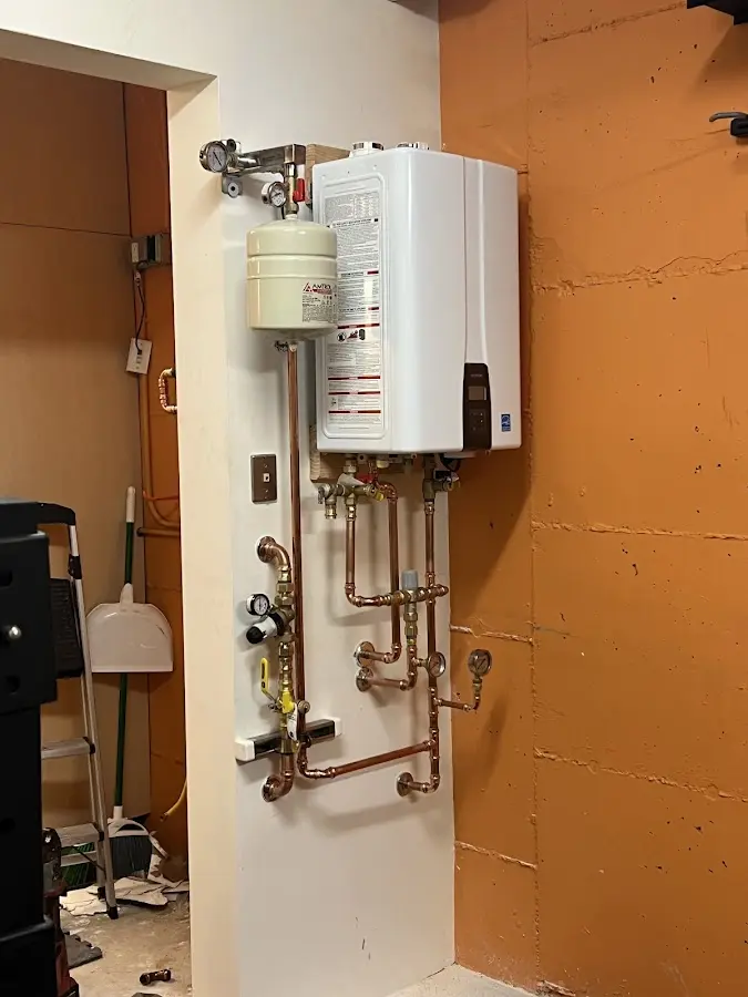 Plumbing technician inspecting water heater connections in Oconto Falls